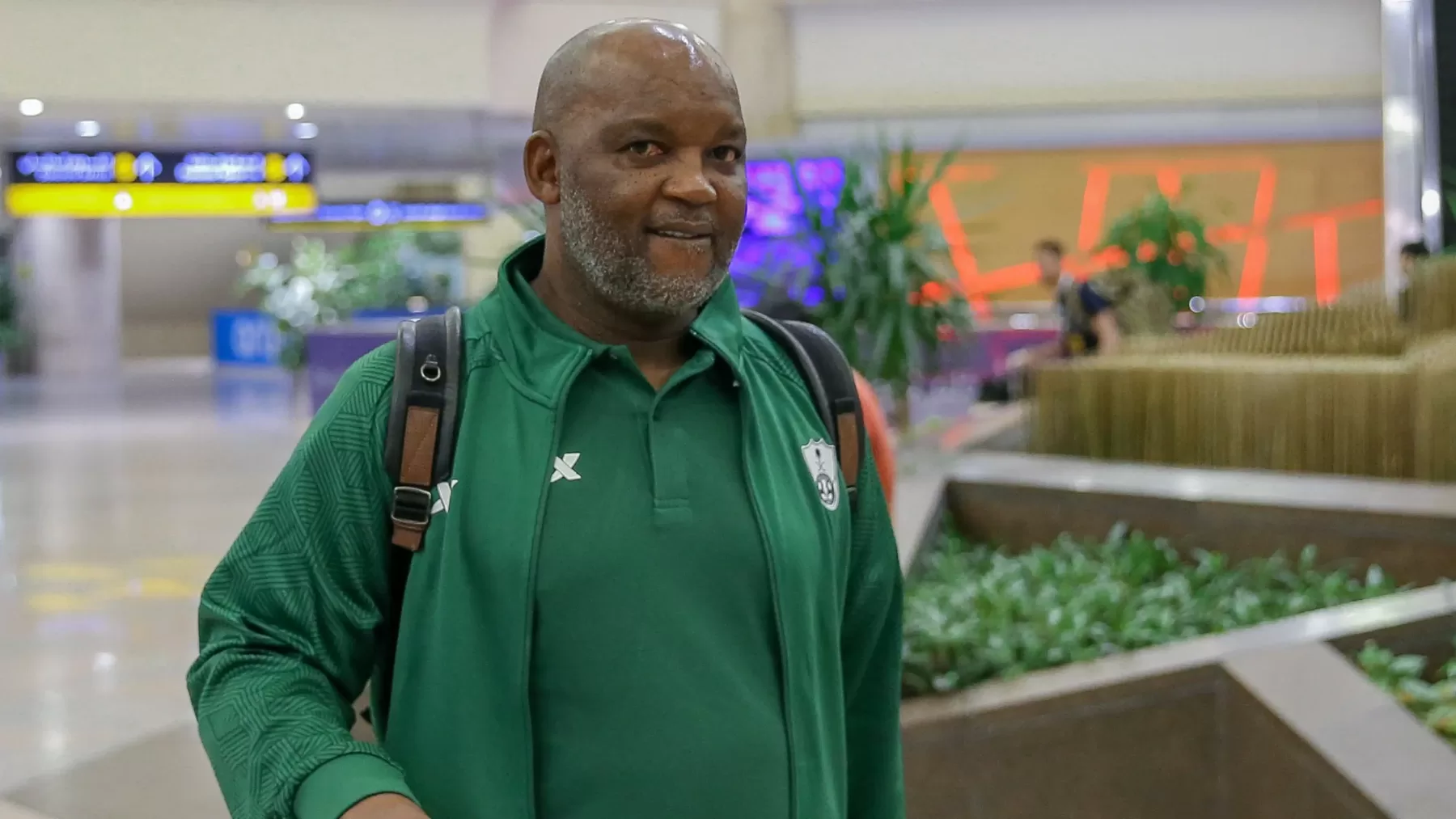Coach Pitso Mosimane walking at an airport