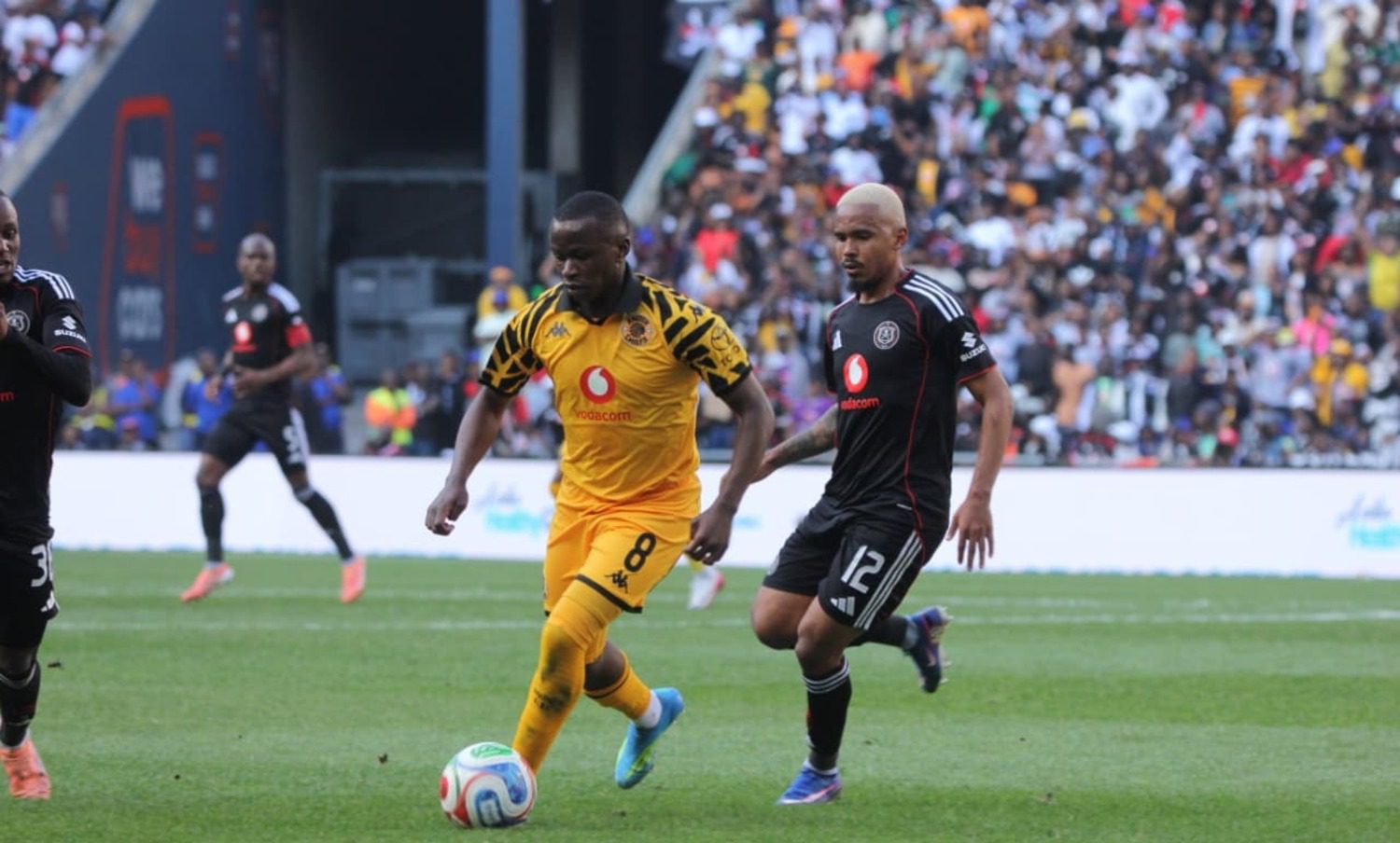Kaizer Chiefs midfielder Siphesihle Ndlovu dribbling the ball past Orlando Pirates winger Oswin Appollis